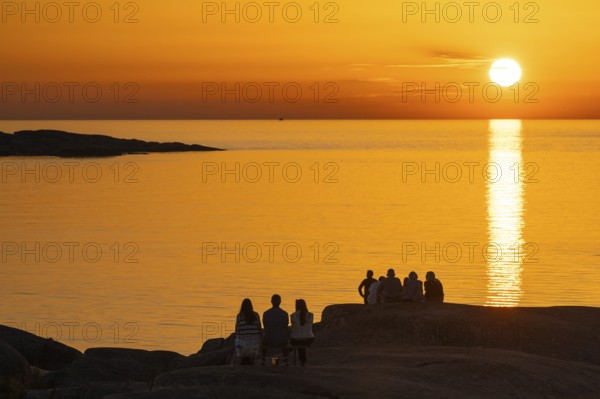 Silhouettes of tourists, sun melting in the sea, sunset, archipelago landscape, Smögen, Smögenbryggan, Västra Götalands Län, Bohuslän, Sweden