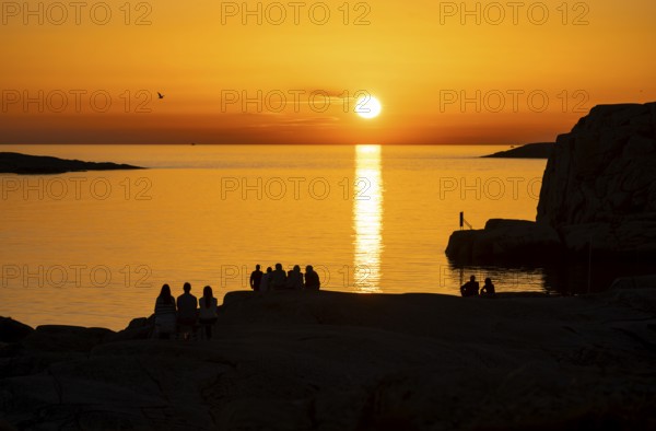 Silhouettes of tourists, sun melting in the sea, sunset, archipelago landscape, Smögen, Smögenbryggan, Västra Götalands Län, Bohuslän, Sweden