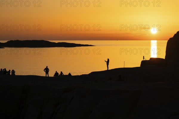 Silhouettes of tourists, sun melting in the sea, sunset, archipelago landscape, Smögen, Smögenbryggan, Västra Götalands Län, Bohuslän, Sweden