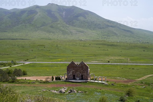 Small stone church in a vast green landscape in front of a mountain with clouds, Saint Trinity Altar of Hope, Aparan, Aragazotn Province, Armenia