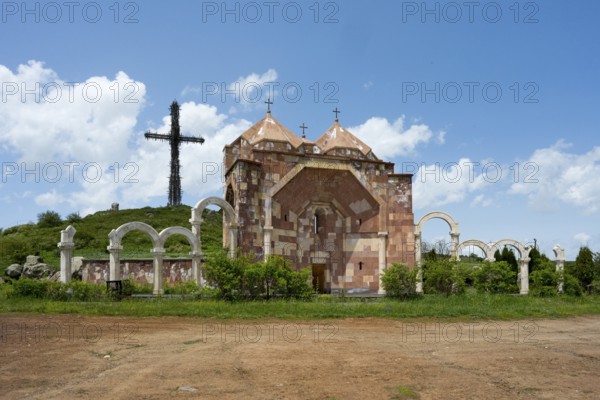 Stone architecture church with arches and cross on a hill under a cloudy blue sky, Monument of the Saint Cross and Saint Trinity Altar of Hope, Aparan, Aragazotn Province, Armenia