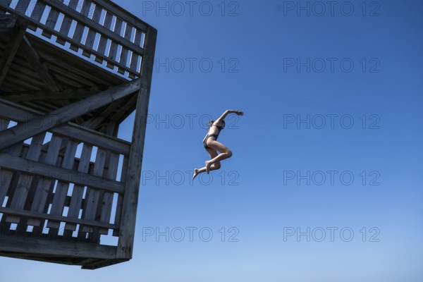 Girl jumping from a high wooden diving platform into the sea, lido, Fjällbacka, Bohuslän, West Sweden, Sweden