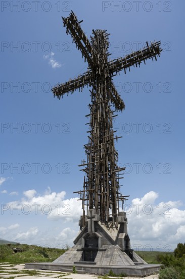 High metal cross with complex structure under a blue sky with clouds, Monument of the Holy Cross, consisting of many small metal crosses, Aparan, Aragazotn Province, Armenia