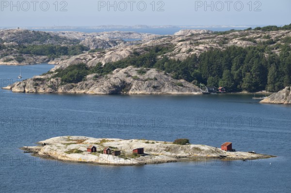 Archipelago landscape with rocks and an offshore archipelago island with falun red woodsheds, Fjällbacka, Bohuslän, West Sweden, Sweden