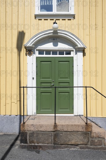 Entrance of a light yellow wooden house with a green door and white door frame, Fjällbacka, Bohuslän, West Sweden, Sweden