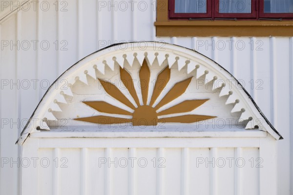 Detail of an ornament symbolising the sun in yellow and white on a wooden house, Fjällbacka, Bohuslän, western Sweden, Sweden