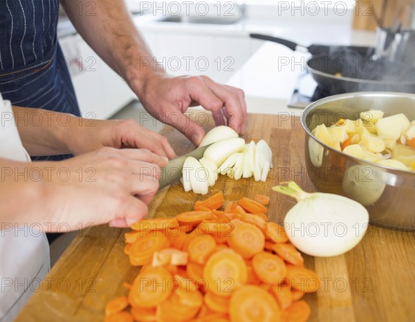 A cozy kitchen scene showing only hands of a couple preparing food, chopping vegetables, and stirring pot, AI generated