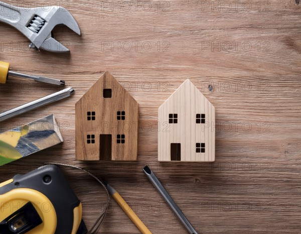 A detailed layout of miniature wooden houses accompanied by various tools on a textured wooden surface, portraying concepts of construction, renovation, craftsmanship, and home improvement, AI generated