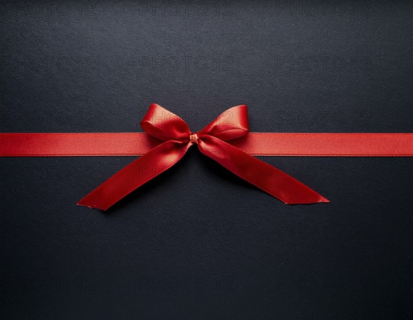 A beautifully wrapped gift box adorned with red satin ribbons forming a bow, contrasting against a linear textured surface, evoking feelings of celebration and elegance, AI generated