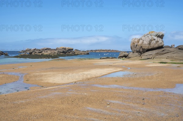 Spectacular pink granite rocks, sculpted by wind and sea, pile up on the beach of the Cote de Granit Rose, while the clear, turquoise-blue water reveals seaweed and light-coloured sand on the seabed at low tide, Tregastel, Cotes-d'Armor department, Brittany region, France