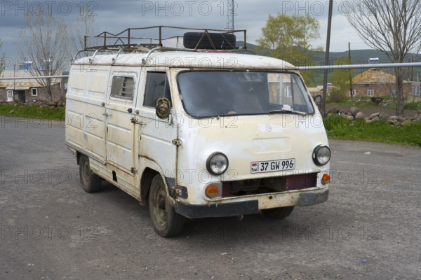 An old white van parked on the side of the road in a rural area, rust decoration visible, van, JerAZ-762 or ErAZ-762, Armenia