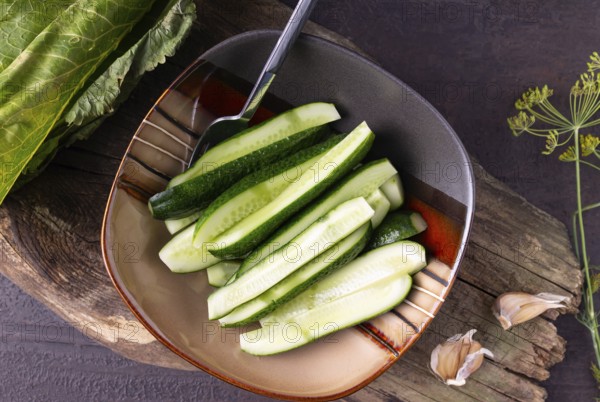 Lightly salted cucumbers in a square plate on a wooden background