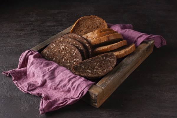 Healthy bread with sprouted grains lies in a wooden box on a pink cloth