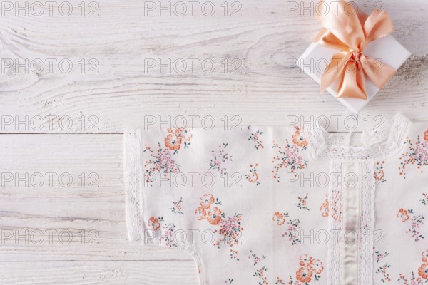 Shirt for newborn toddler and gift box on white wood