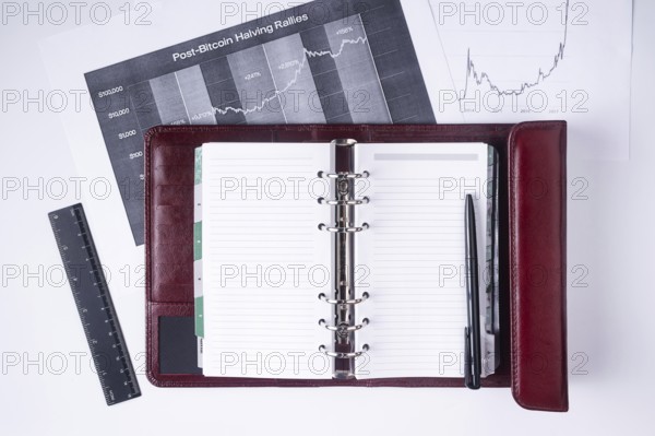 A notebook with a pen lies on financial charts