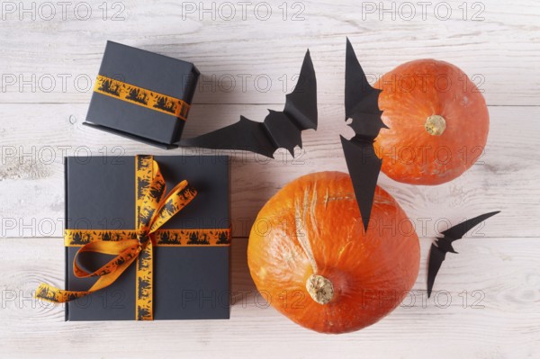Pumpkin gifts black paper bats on light wood flat lay halloween decor