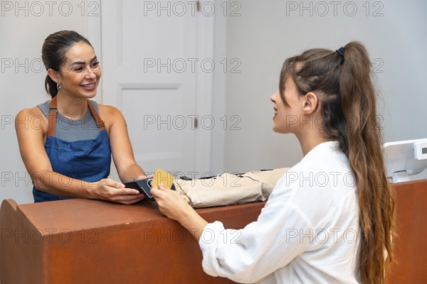 Shop assistant smiling and accepting a credit card payment from a customer in a small clothing store