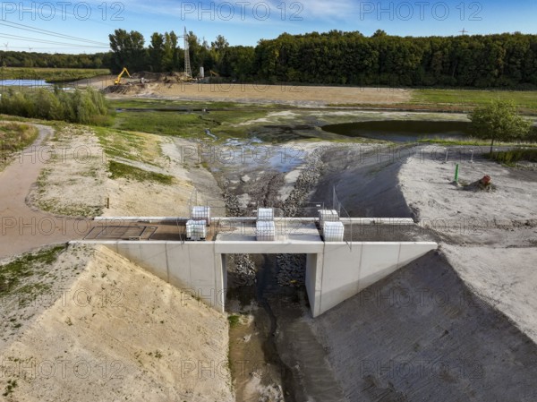 Dortmund, Castrop-Rauxel, North Rhine-Westphalia, Germany - River renaturalisation, renaturation of the Emscher, flood retention basin HRB Mengede. Heimanngraben intake in front, construction of a bridge over the ditch. A new floodplain landscape is being created at the Emscher-Auen farm, expansion of the area for flood protection during heavy rainfall and for biodiversity. The previously straightened Emscher is given curves again and can meander through its new floodplain. Following the construction of a parallel sewer, the Emscher has been completely free of sewage since 2022. The river was previously an open, above-ground combined sewer with rainwater and wastewater