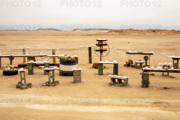 Pink salt displayed on wooden stands along the road to Namib-Naukluft National Park and Sandwich Harbour, Namibia, set against a desert landscape