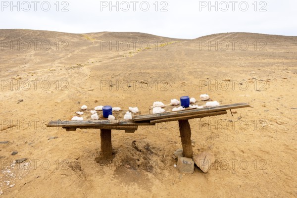 Pink salt displayed on wooden stands along the road to Namib-Naukluft National Park and Sandwich Harbour, Namibia, set against a desert landscape