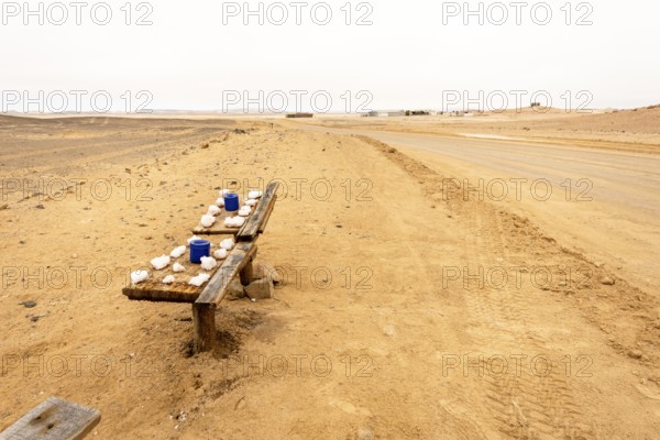 Pink salt displayed on wooden stands along the road to Namib-Naukluft National Park and Sandwich Harbour, Namibia, set against a desert landscape