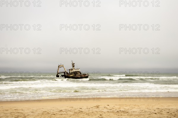 The Zeila shipwreck off Namibia's Skeleton Coast, rusting in the Atlantic surf under cloudy skies with seabirds perched on its frame