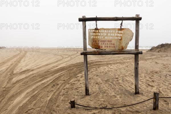 Road sign displaying the name of Namib-Naukluft National Park against a desert landscape under a cloudy sky, Namibia - 30 August, 2025