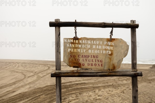 Road sign displaying the name of Namib-Naukluft National Park against a desert landscape under a cloudy sky, Namibia - 30 August, 2025
