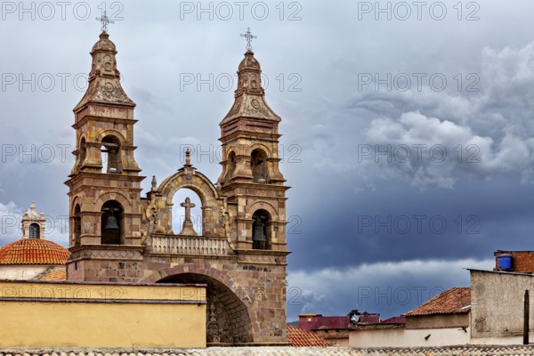 Historic church with imposing spires against a dramatic, cloudy sky, Cathedral spires over the city of Potosi in Bolivia
