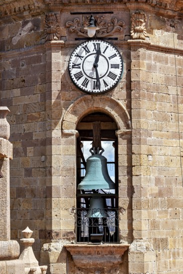 Detail of a clock tower with a large clock and a visible bell in a colonial building, The churches of the city of Potosi in Bolivia