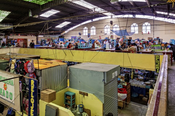 Interior view of a multi-storey market with many stalls and a busy atmosphere under an industrial ceiling, inside the market halls of Potosi Bolivia