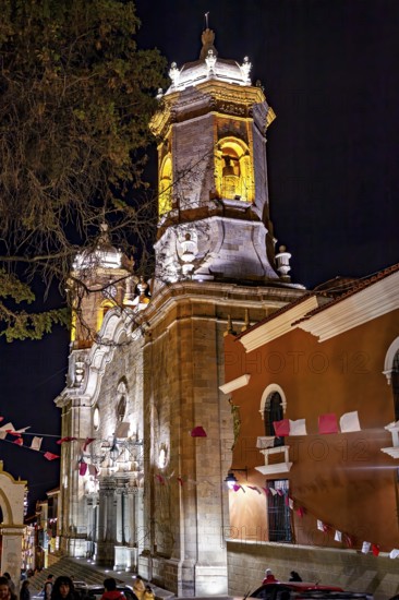 Illuminated church at night, decorated with flags and surrounded by trees, The churches of the city of Potosi in Bolivia