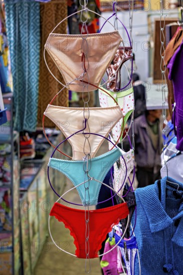Colourful underwear hanging on chains in a lively market shop, selling women's panties in the market halls of Potosi Bolivia