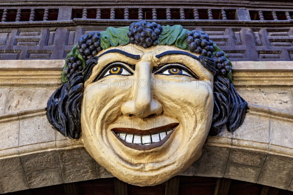 Large, smiling face made of stone and wood, richly decorated as an architectural detail of a building, The face in the inner courtyard of the museum of the city of Potosi in Bolivia