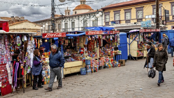 Colourful market stalls with Coca-Cola signs on a busy pavement full of people, Small market stalls in the centre of Potosi in Bolivia