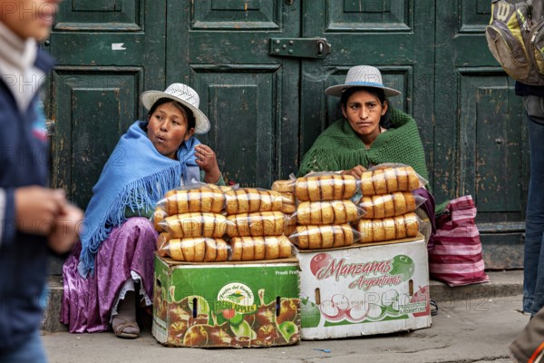 Two woman in traditional dress selling bread on the street, Bolivian Indio woman selling goods in the streets of Potosi Bolivia