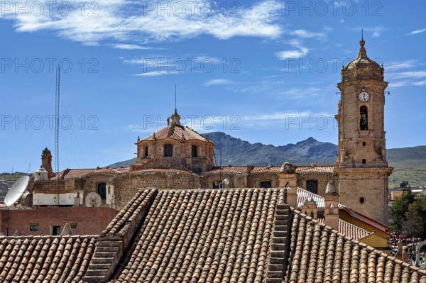 Cityscape with an old clock tower, surrounded by many roofs and mountains in the background, The churches of the city of Potosi in Bolivia