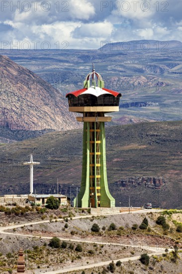 Observation tower on a hill with a cross in front of a mountain range and clouds, The water tower of the city of Potosi in Bolivia