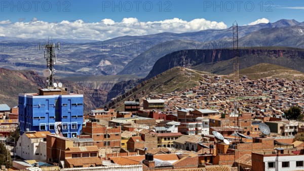 Urban landscape with red tiled roof architecture and a telecommunications tower in front of a cloudy mountain landscape, view over the city of Potosi in Bolivia