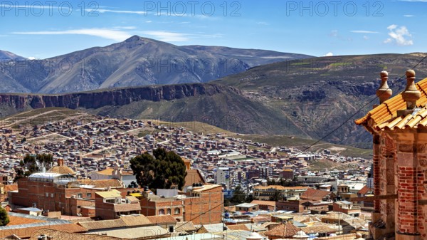 A city with tiled roofs and a mountain landscape in the background under a clear blue sky, view over the city of Potosi in Bolivia