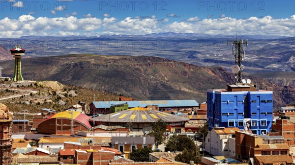 View over a city with colourful roofs and a telecommunications tower, surrounded by mountains under a blue sky, view over the city of Potosi in Bolivia
