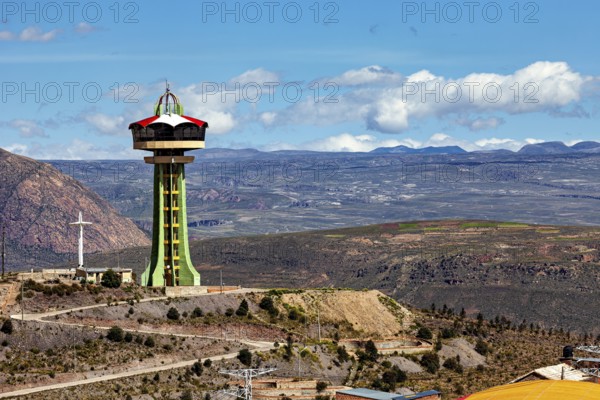 Observation tower on a hill with a cross and clouds in the blue sky in the background, The water tower of the city of Potosi in Bolivia