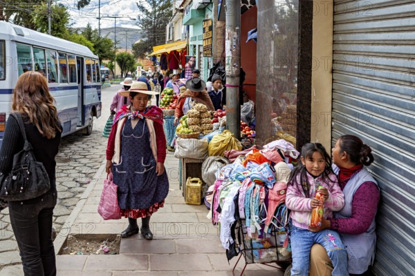 Street with vendors, fruit and clothes, busy with passers-by and a bus, people in the streets of Potosi in Bolivia