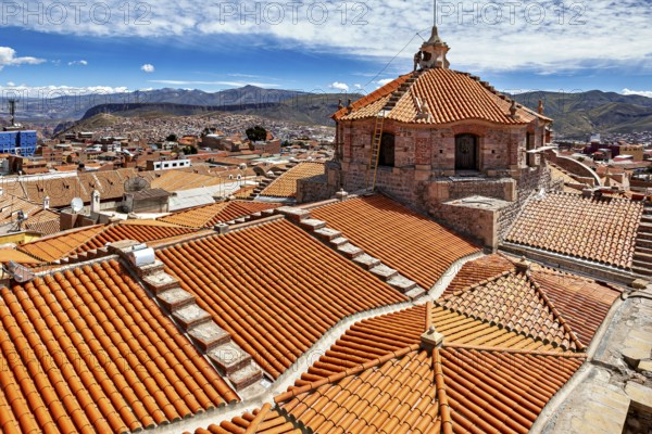 Red roof tiles of a city with colonial architecture, surrounded by mountains under a blue sky, The roof of the cathedral of Potosi in Bolivia