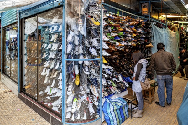 Shoe shop with shelves full of colourful shoes and people shopping, people in the streets of Potosi in Bolivia