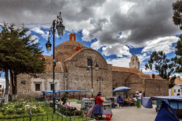 Small church with a round dome next to a busy market square under a partly cloudy blue sky, The old churches of Potosi in Bolivia