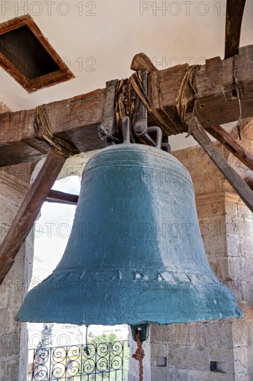 Large bell in an old tower made of wood and stone, with a bright sky in the background, The large bell of Potosi Cathedral in Bolivia