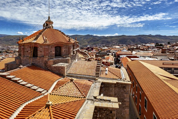 Colonial building with traditional roof tiles and mountain backdrop under a blue sky, The roof of Potosi Cathedral in Bolivia