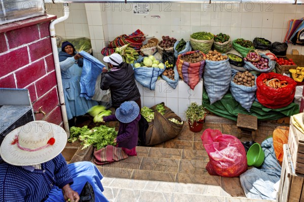 Women arranging vegetables in colourful sacks at a market stall in Bolivia, selling goods in the market halls of Potosi in Bolivia