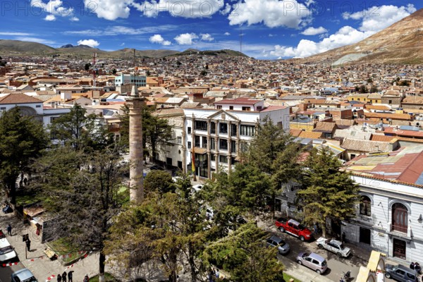 Sweeping view over rooftops of a city with surrounding mountains and blue sky, view over the city of Potosi in Bolivia